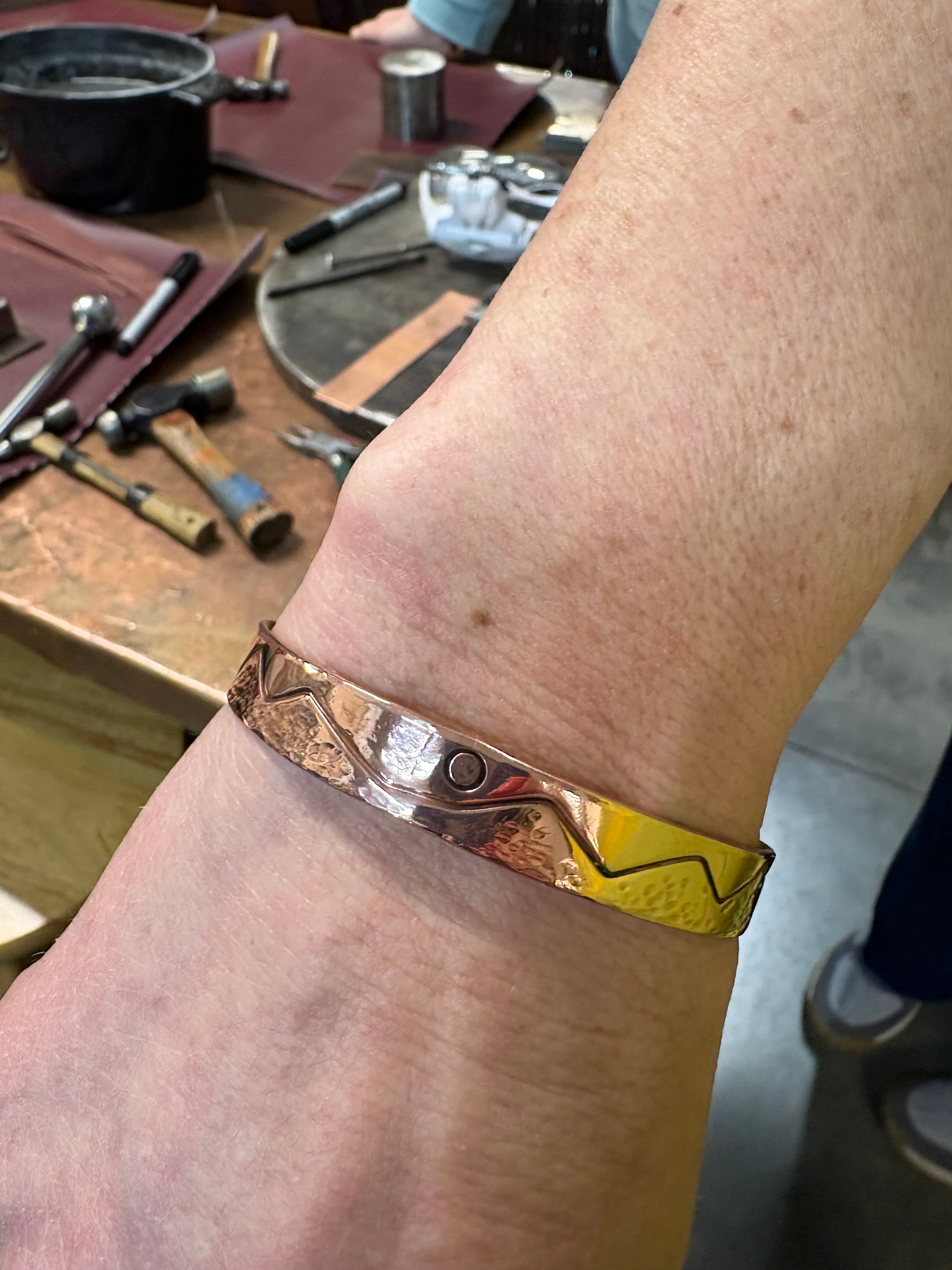 Gold bracelet on a wrist with a workshop background