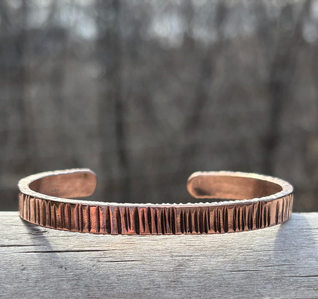 Copper bracelet on a wooden surface with a blurred natural background