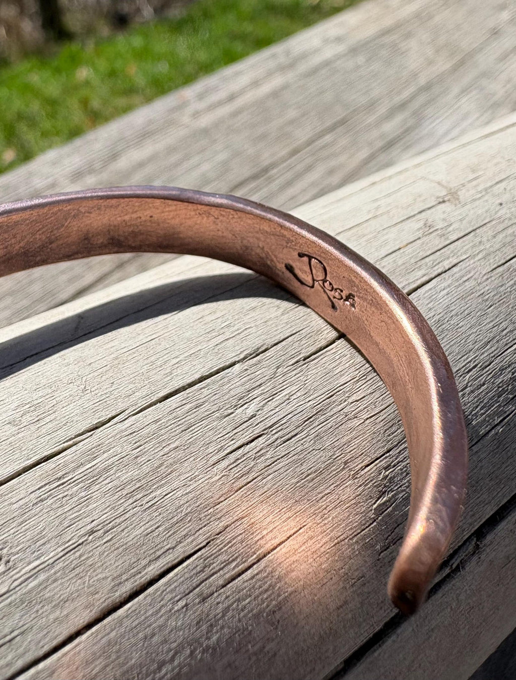 Copper bracelet with engraved name on a wooden surface