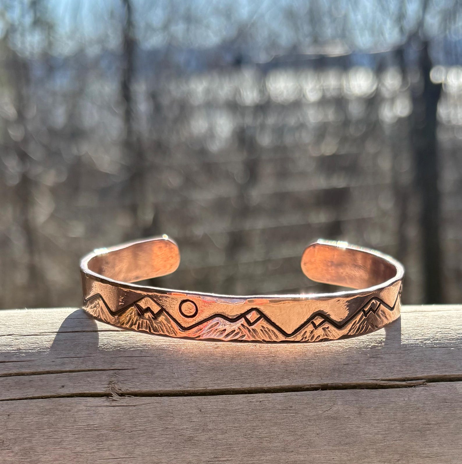 Copper bracelet with mountain design on a wooden surface