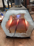Copper block being heated in a forge with glowing metal