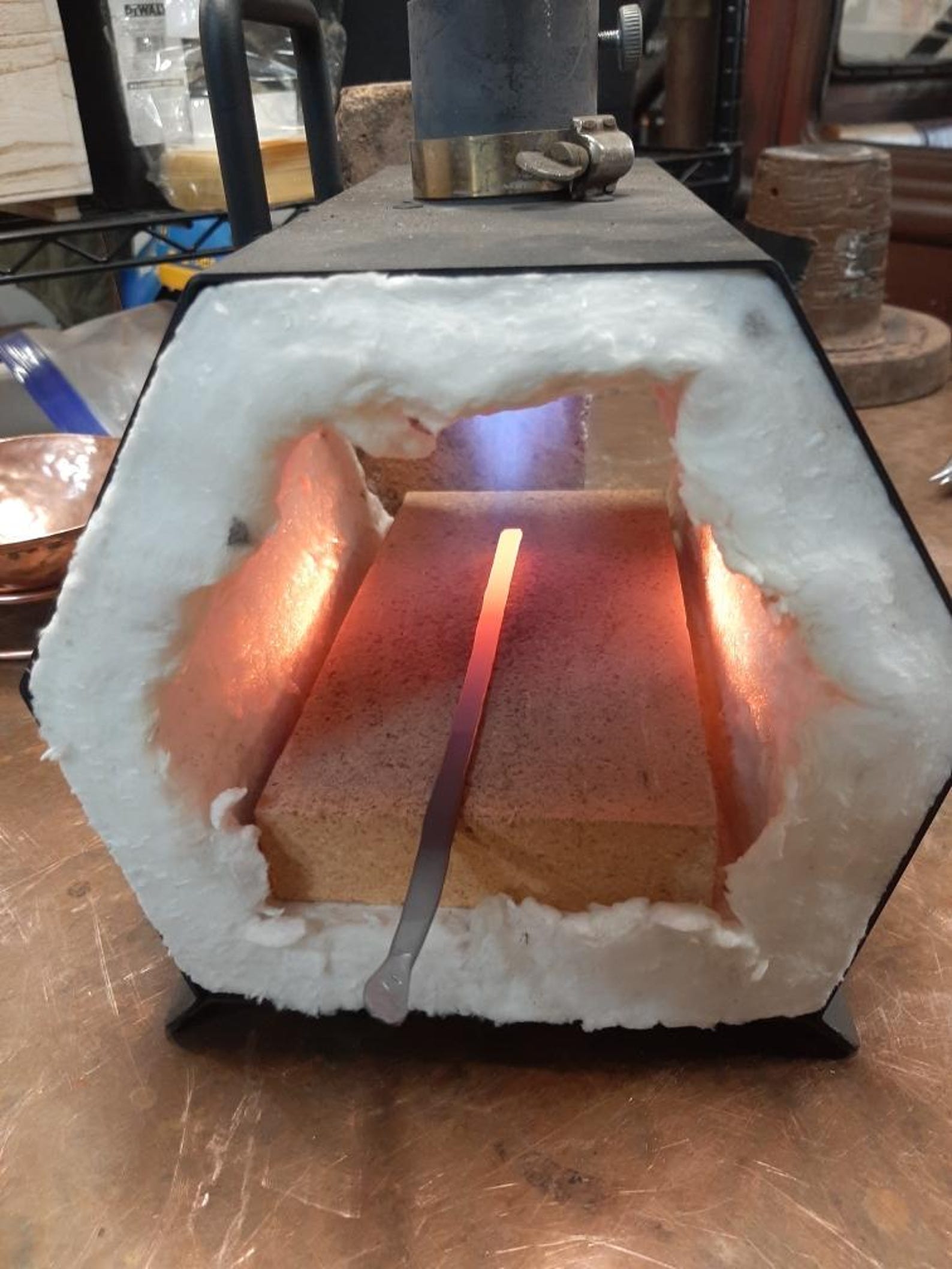 Copper block being heated in a forge with glowing metal