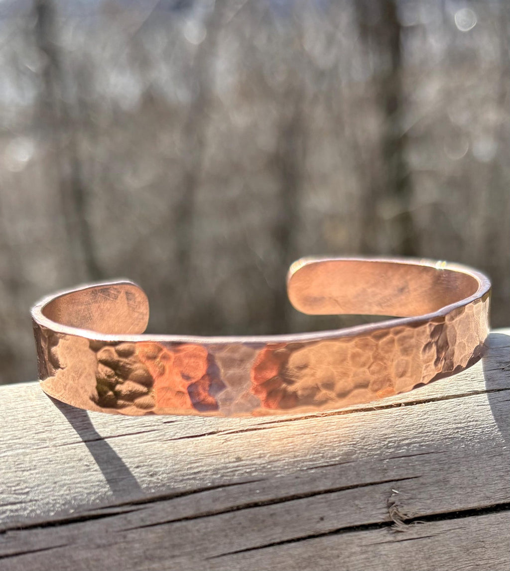 Copper bracelet on a wooden surface with a blurred natural background