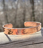 Copper bracelet on a wooden surface with a blurred natural background
