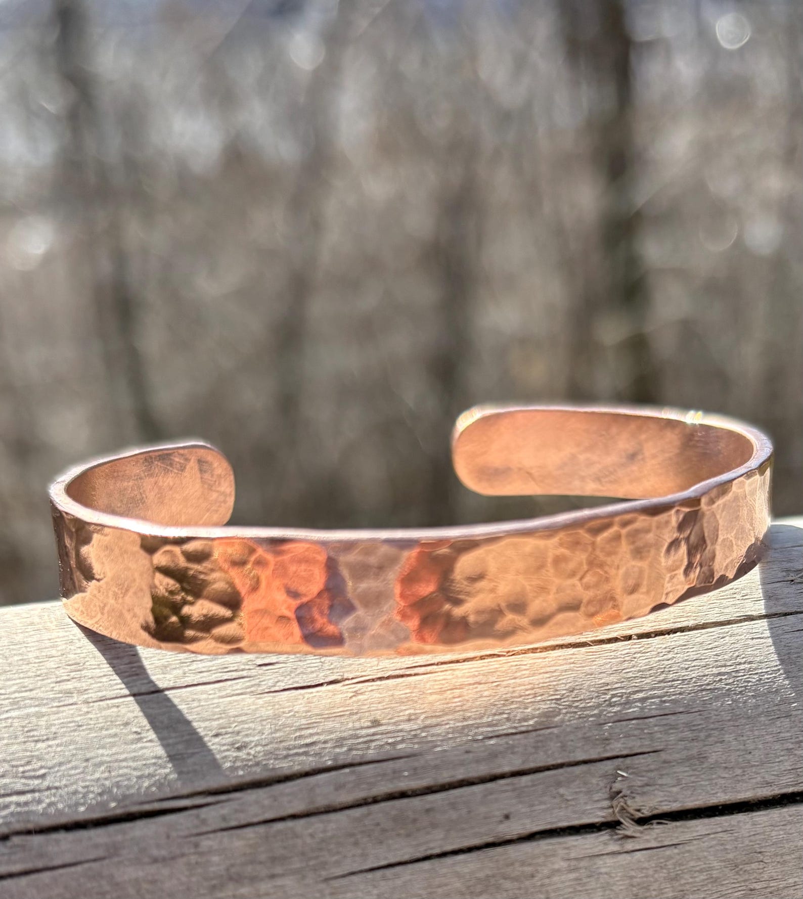 Copper bracelet on a wooden surface with a blurred natural background