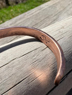 Copper bracelet with engraved name on a wooden surface