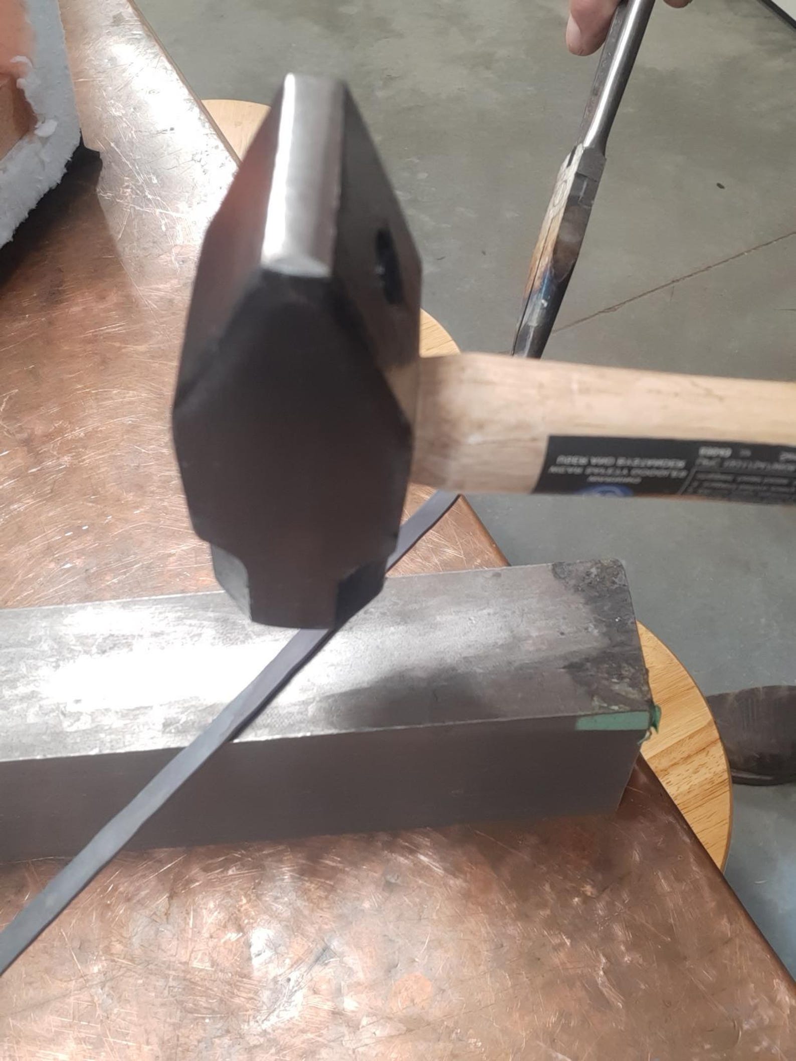 Metal file being sharpened on a stone with a hammer in the background
