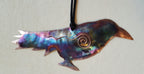 Decorative metal fish ornament with a spiral design on a light gray background