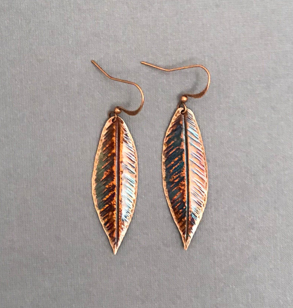 Copper leaf-shaped earrings on a gray background