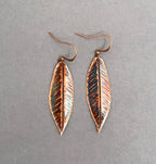 Copper leaf-shaped earrings on a gray background