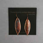 Copper leaf-shaped earrings on a card with 'Handcrafted Copper Originals by John Rose' text.