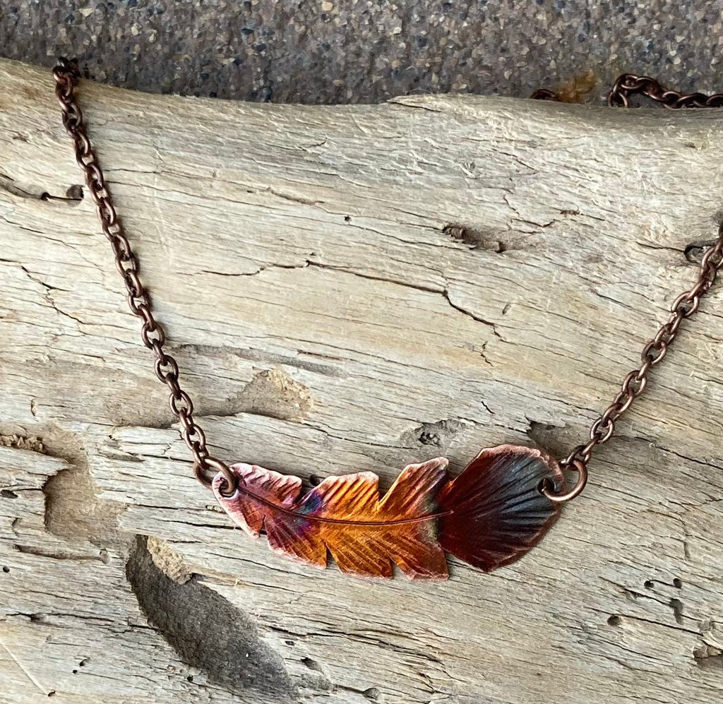 Necklace with feather pendant on a wooden surface