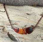 Necklace with feather pendant on a wooden surface