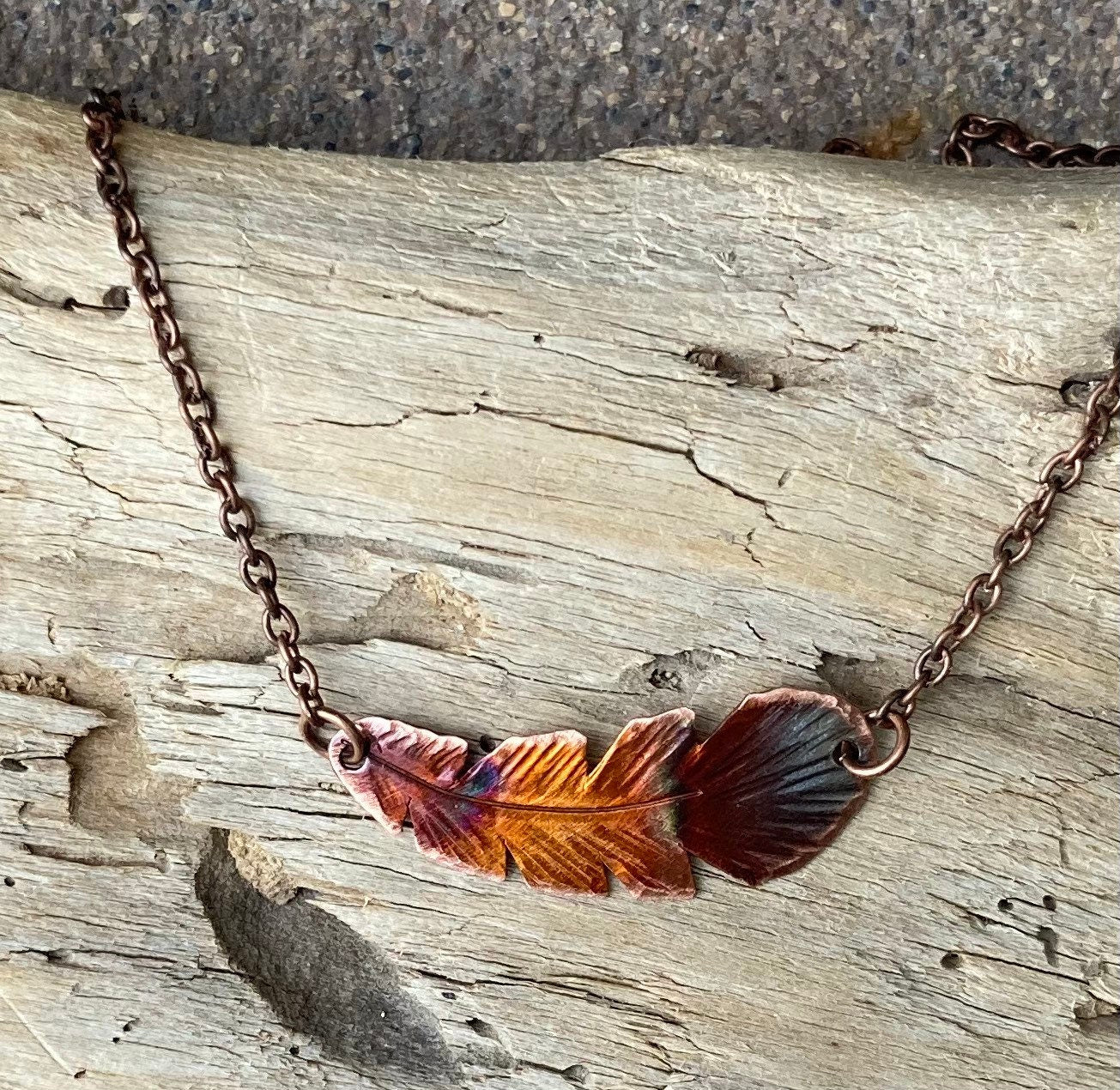 Necklace with feather pendant on a wooden surface