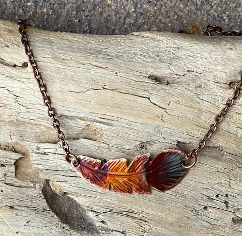 Necklace with feather pendant on a wooden surface