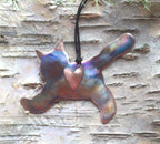 Metallic pendant shaped like a cat with a heart on a wooden surface