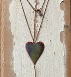 Heart-shaped pendant necklace on a textured wooden surface