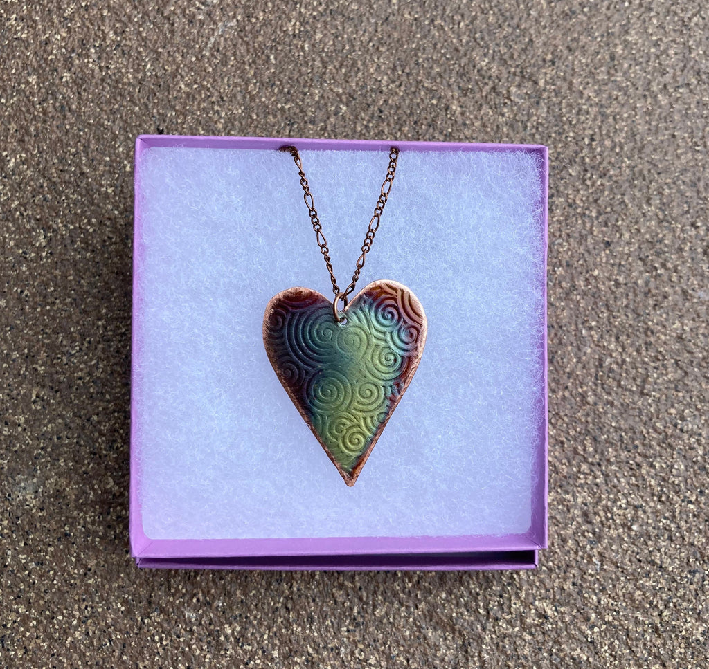 Heart-shaped pendant necklace on a purple card with a textured background