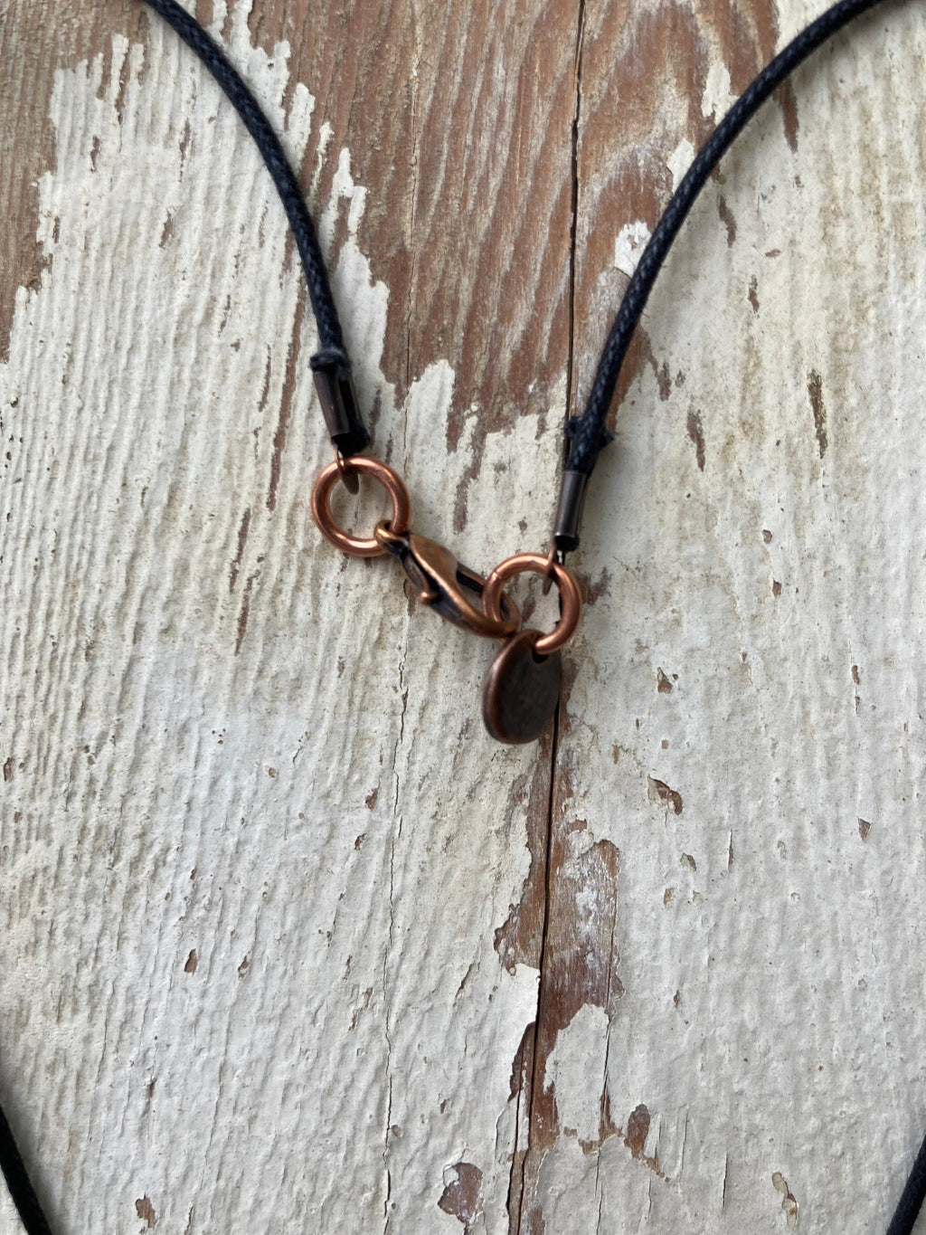 Necklace with copper clasp on a wooden surface