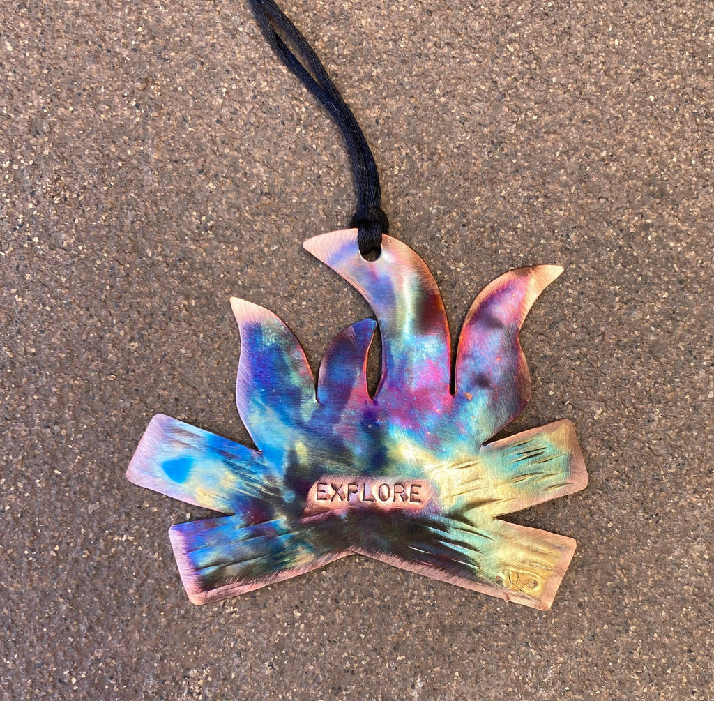 Colorful campfire ornament with 'EXPLORE' engraving on a textured surface